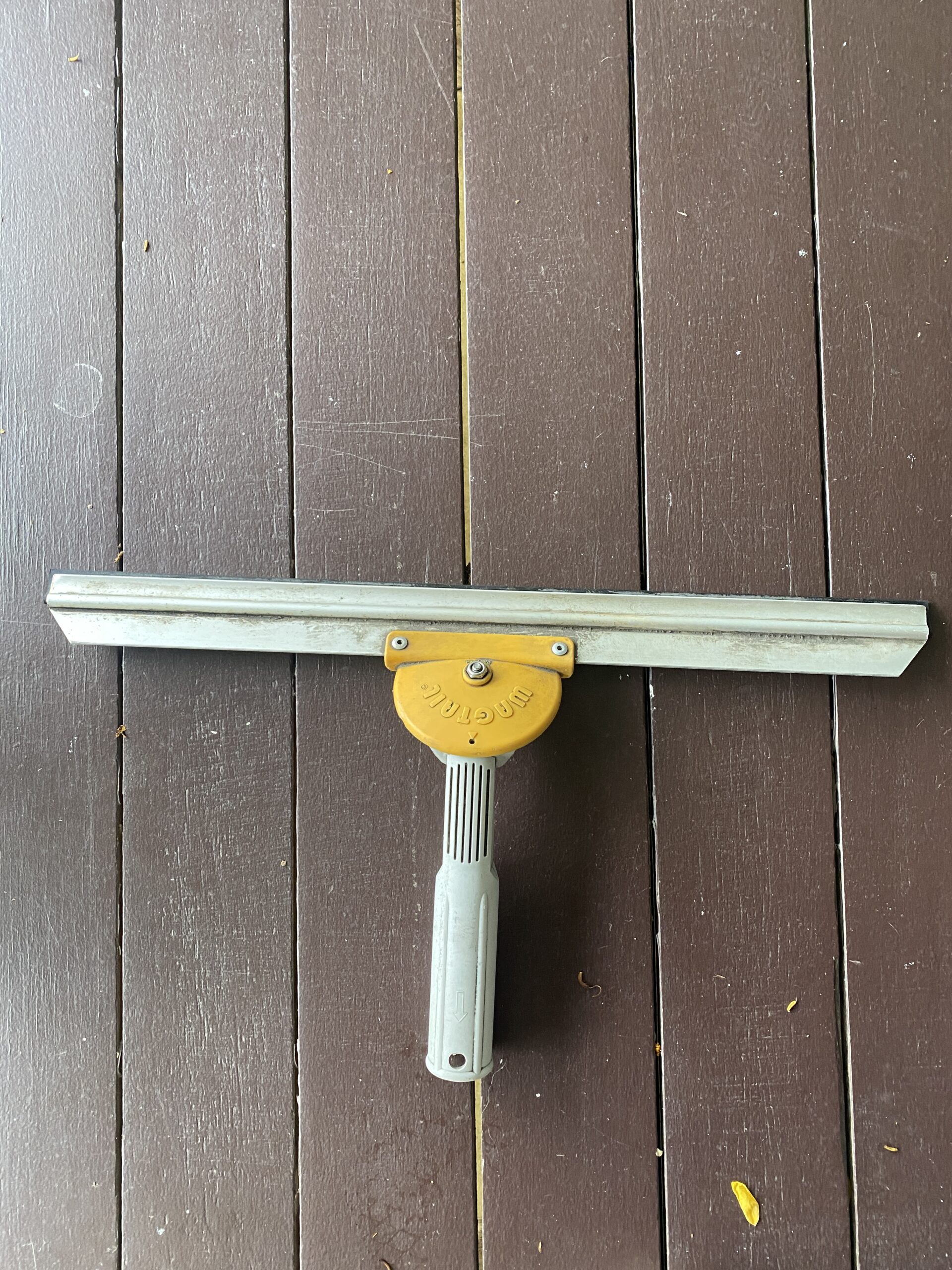 Professional window squeegee removing water from glass in a single stroke